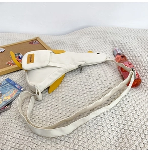 Detail of white canvas duck cross-body bag with zipper, yellow wings and adjustable strap