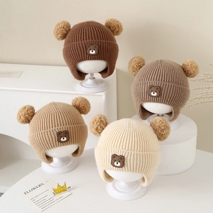 Winter knit baby earflap hat with double pom poms and cute bear patch in earth tones