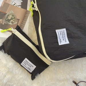 Macro detail of black pleated nylon travel organizers with neon zippers on soft white rug