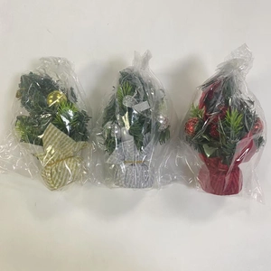 Three mini Christmas trees with gold, silver and red bases in clear packaging