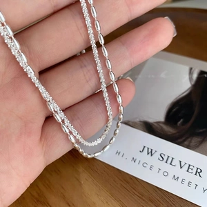 Double-layered silver necklace with polished capsule beads and shimmering woven chain