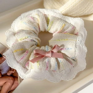 Detail of cream tweed hair scrunchie with colorful stitching and delicate white lace trim