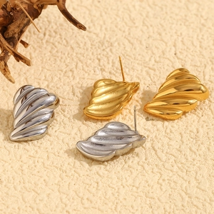 Macro detail of textured wing earrings in gold and silver finish with surgical steel posts