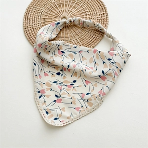 Detailed macro view of floral cotton headscarf with cream lace trim on a woven mat
