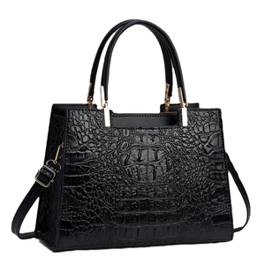 Elegant black crocodile-textured handbag with gold hardware and removable strap