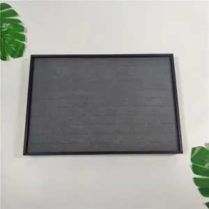Top view of jewelry tray showing rows of grey velvet slots for rings and earrings