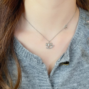 Gros plan d'un collier pendentif cheval à bascule en argent serti de zircons sur un mannequin