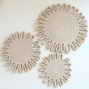 Three-piece set of beige braided cotton table mats in varying sizes with loop edge details