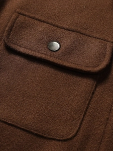 Close-up of deep brown corduroy jacket pocket with silver metal snap button detail