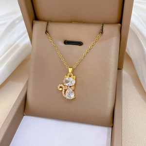Détail d'un collier pendentif chat doré avec zircons dans un coffret cadeau de luxe