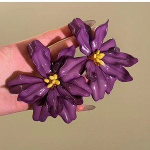 Macro detail of large purple acrylic floral earrings with polished resin petals
