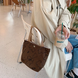 Detail of corduroy tote bag with bear print and snap button on a white chair