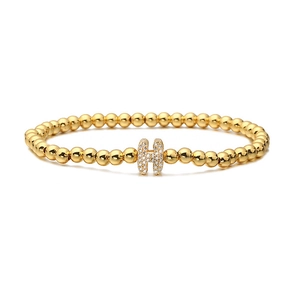 Close-up of golden beaded stretch bracelet with a micro-pave zircon H letter charm