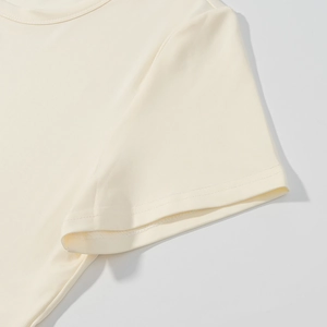 Dettaglio maglietta in maglia beige con scollatura e cuciture doppie sulla manica