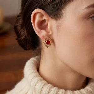Boucle d'oreille vintage dorée avec rubis rouge sur un mannequin en pull beige