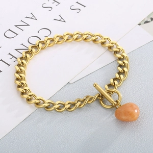 Close-up of golden OT buckle chain bracelet with an orange heart stone pendant