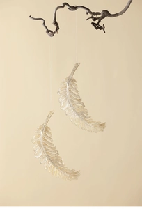 Close-up of elegant semi-transparent gold pink feather ornaments hanging on a branch