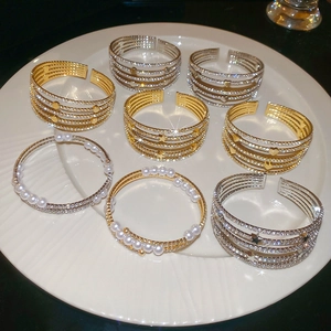 Detailed view of multilayer pearl heart and star open bangles with sparkling rhinestones