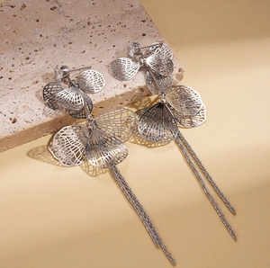 Détails de boucles d'oreilles à pompon argenté avec pétales creux et pierres zircons