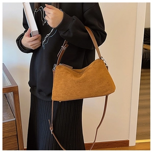 Close-up of brown suede shoulder bag with metal buckle and soft vintage texture detail