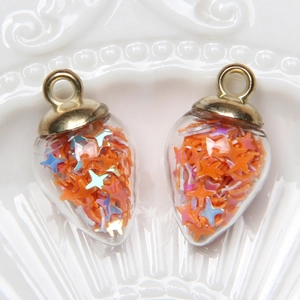 Macro detail of glass waterdrop pendants filled with orange star shaped sequins