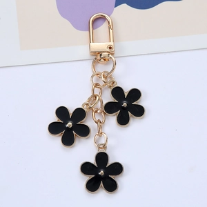 Chic gold-plated keychain with triple black enamel flowers and lobster clasp on white background