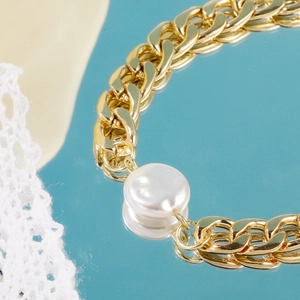 Macro shot of Baroque irregular pearl on a thick golden Cuban chain bracelet with lace detail