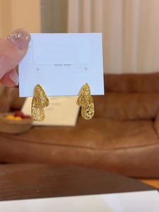 Dettaglio di orecchini a goccia in oro e argento S925 con motivi cavi e piccoli diamanti