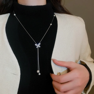 Detailed view of elegant silver butterfly necklace with zircons and hanging white pearls
