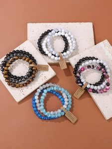 Detail view of multi-layered natural stone bracelets on beige textured stone slabs