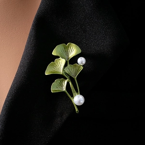 Detailed shot of green ginkgo leaf brooch with pearls pinned on a black suit lapel