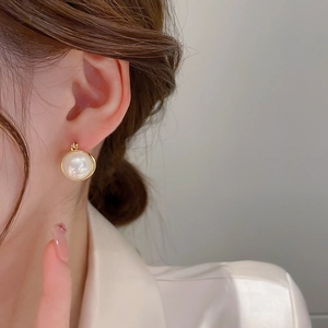 Close-up of elegant gold pearl earrings on a model with minimalist style