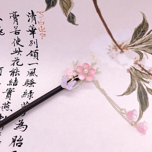 Detailed close-up of pink peach blossom hair stick with butterfly tassel and wooden base