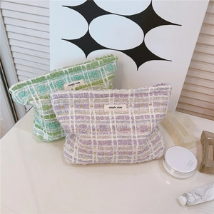 Detail of tweed makeup bags in green and purple plaid with simple wish fabric label