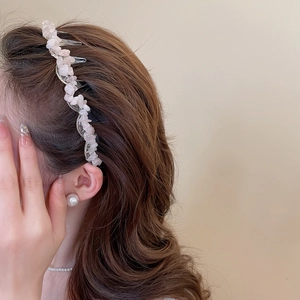 Detail view of pink acrylic irregular stone headband worn on brown wavy hair