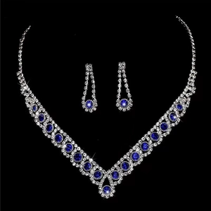 Macro detail of V-shaped silver necklace and earrings set with deep blue gemstones