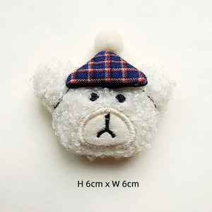 Detail of 6cm white plush bear head with plaid hat and embroidered facial features