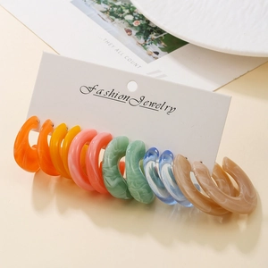 Close-up of colorful C-shaped acrylic earrings set with marble and solid textures