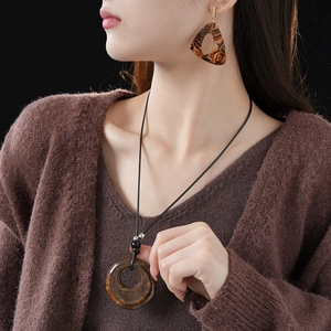Detail of amber leopard print resin necklace and triangle earrings set on a model