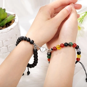Close-up of magnetic heart clasp connecting natural tiger eye and matte stone bracelets