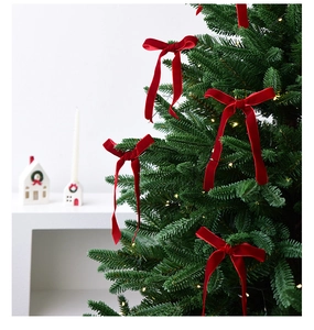 Red velvet Christmas bows decorated on a green tree for a warm festive atmosphere