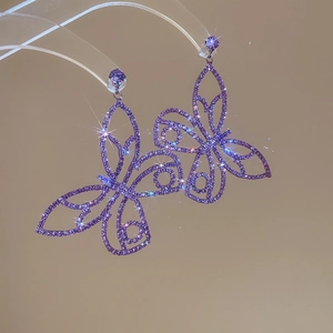 Detailed view of luxury purple butterfly earrings with zircon inlay on transparent stand