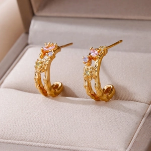 Detailed macro view of gold-plated C-shaped earrings with rose motifs and colorful gems