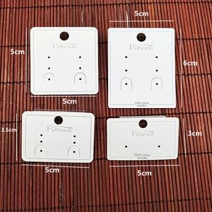 Detailed view of four white PVC earring display cards in various sizes with Fashion text