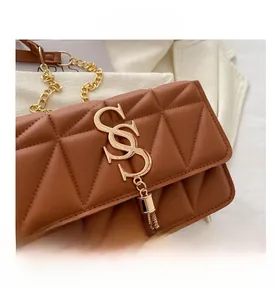 Detailed close-up of brown quilted faux leather bag with gold S-buckle and tassel