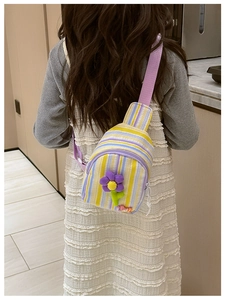 Detailed view of child wearing a striped crossbody bag with a 3D floral accent