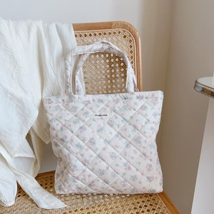 Quilted floral cotton tote bag with pink and blue flowers on a vintage wicker chair