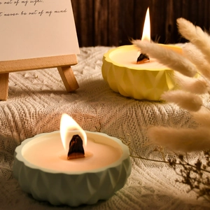 Close-up of ripple-textured candle molds with wood wicks and warm flickering light