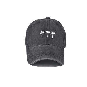 Close-up of white coconut tree embroidery on a washed dark gray denim baseball cap