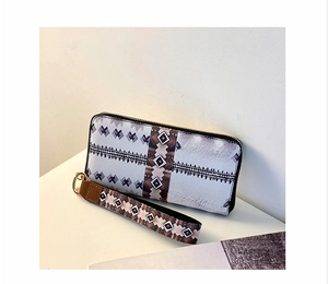 Close-up of long zip wallet with ethnic geometric patterns and brown leather wrist strap